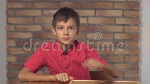坐在书桌前的孩子拿着一张挂图上面写着红砖墙上的头奖视频的预览图