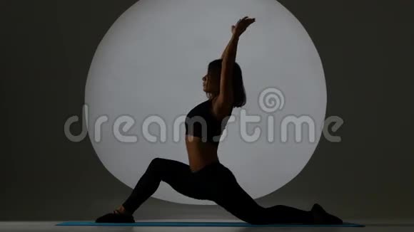 体操运动员坐在劈腿上双手伸向一条腿背光轮廓视频的预览图