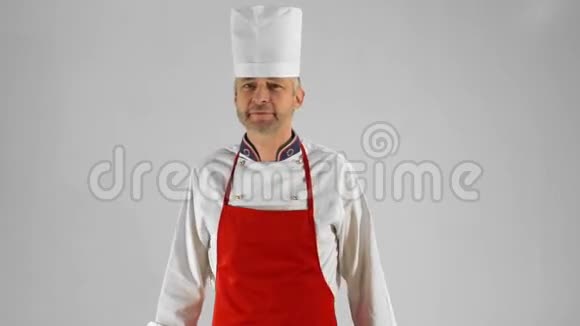 英俊的成年厨师转过身来他用刀叉交叉双臂头在灰色背景上点点头视频的预览图