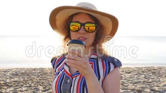 在海滩上喝咖啡的年轻女子视频的预览图
