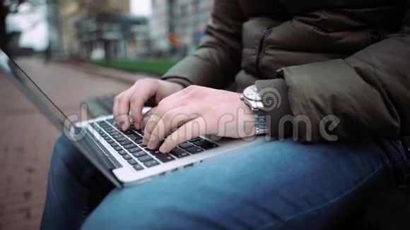 顶部查看男性手使用笔记本户外在城市设置同时打字键盘4k视频的预览图