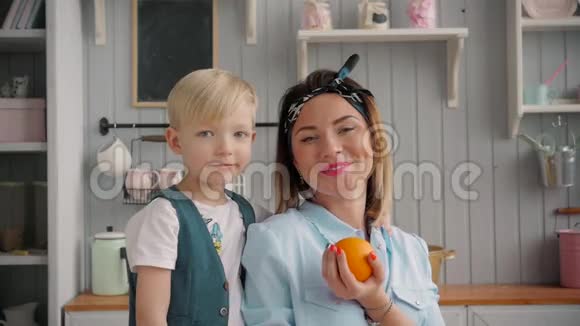 快乐的妈妈和小儿子在厨房里快乐的时光和相聚妈妈抱着新鲜的橘子视频的预览图