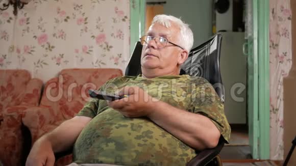 老人坐在皮椅上专心看电视戴着眼镜白发视频的预览图