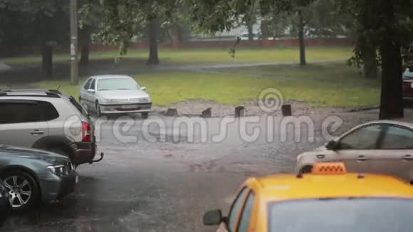 雨水倾泻在人行道上出租车和汽车变成了洪水另一辆车经过下面的水溅到周围视频的预览图