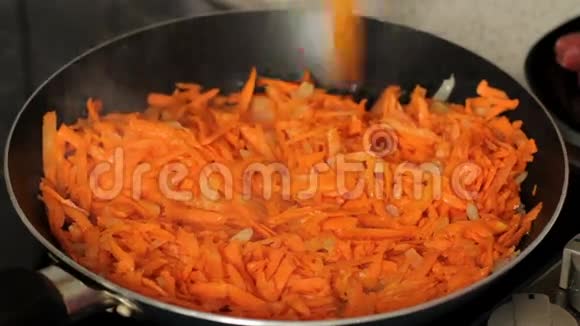 煎炸时用木铲把胡萝卜和洋葱搅在一起快关门红萝卜炒在煎锅上视频的预览图