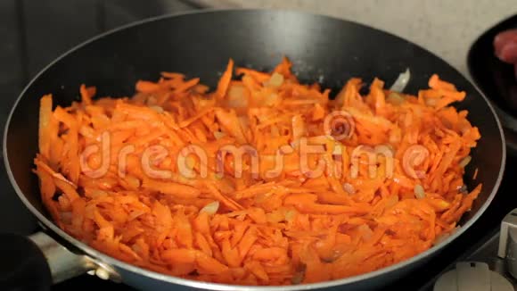 红萝卜炒在煎锅上油炸时有胡萝卜和洋葱的蒸汽特写视频的预览图