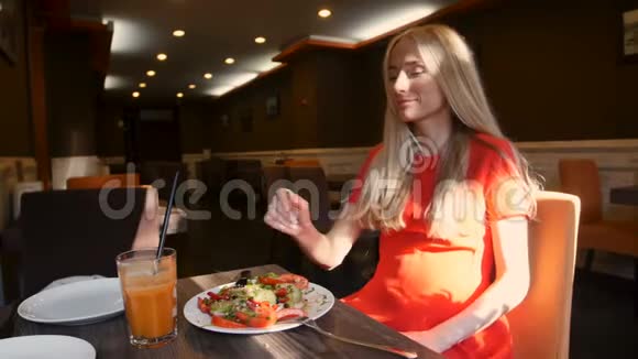 穿红裙子的女人在咖啡馆里吃新鲜沙拉视频的预览图