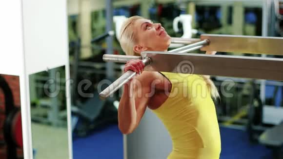 女孩做一个拉力运动在水平杆上做运动运动的女人在健身房里做运动视频的预览图