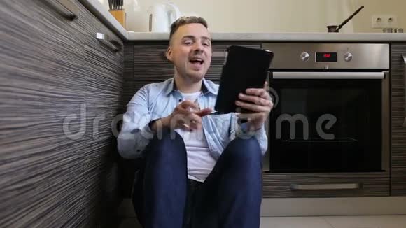 男人在厨房的平板电脑上聊天视频的预览图