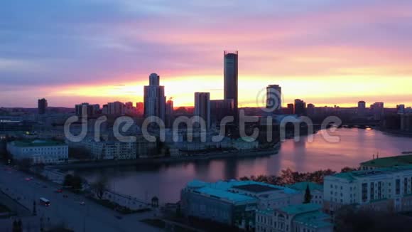 日落时美丽的城市和河流的鸟瞰视频的预览图