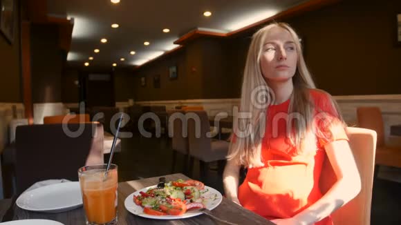穿红裙子的女人在咖啡馆里吃新鲜沙拉视频的预览图