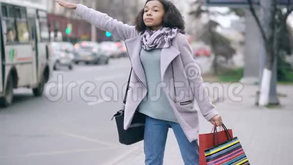漂亮的非洲裔美国妇女带着购物袋从商场销售回来的时候叫出租车视频的预览图