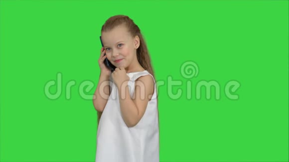 可爱的小女孩在绿色屏幕上的手机上说话色度键视频的预览图