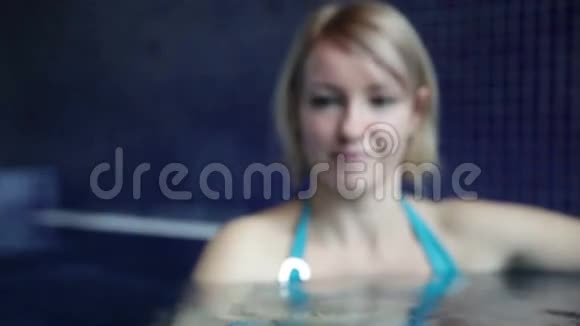 泳池里穿着蓝色比基尼的年轻女子正在向某人挥手视频的预览图