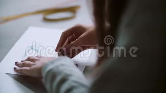 年轻女子用蓝鞋素描擦在纸上的背面设计师坐在桌子旁开发布局4K视频的预览图