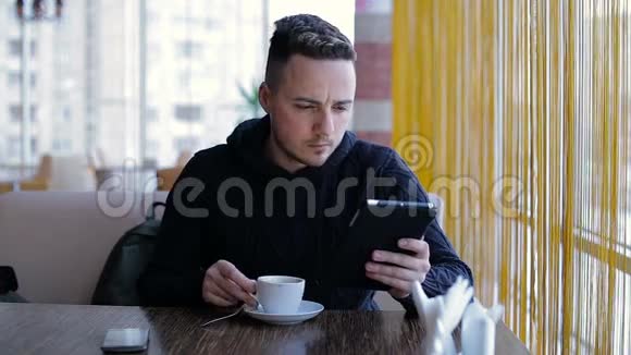 带着平板电脑的年轻人在咖啡厅喝咖啡视频的预览图