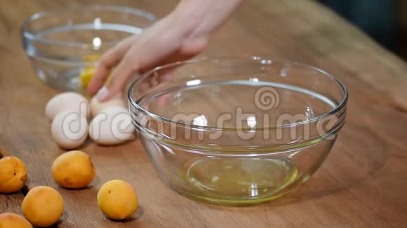 女人的手打破一个鸡蛋以分离蛋清和蛋黄和鸡蛋壳的背景视频的预览图