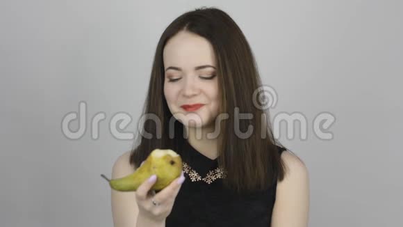 美丽的年轻女子吃着绿梨微笑着视频的预览图