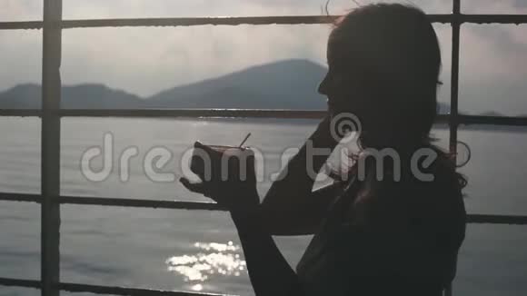 年轻的忧郁的女孩坐在货轮上的长凳上从纸杯里喝咖啡眺望大海1920x1080视频的预览图