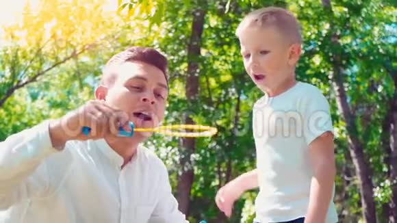 父亲和儿子吹肥皂泡家庭娱乐孩子和父亲玩得开心视频的预览图