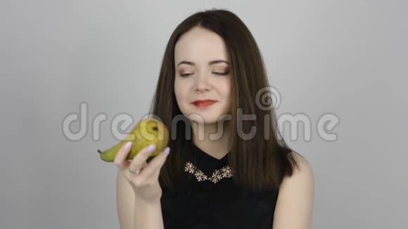 美丽的年轻女子吃着绿梨微笑着视频的预览图
