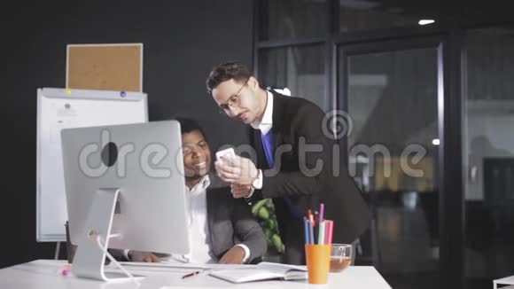 男人在办公室给他的同事看一个电话项目视频的预览图