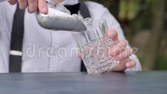 酒吧老板把冰块放进酒吧柜台的玻璃里酒吧老板把冰块放进杯子里用来喝酒鸡尾酒会视频的预览图