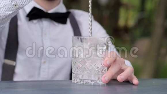 酒吧柜台上装有冰块的玻璃杯酒吧招待搅拌冰酒吧勺子特写酒保将饮料冷却到新鲜空气中视频的预览图