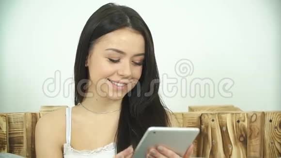 美丽的女孩使用平板电脑和绿色屏幕躺在家里的床上视频的预览图