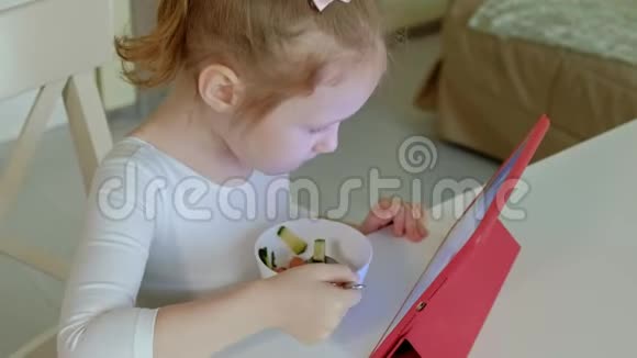 小女孩吃和玩电脑平板电脑网上冲浪视频的预览图