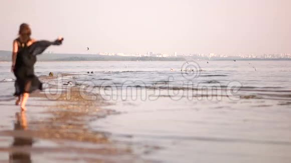 女孩在城市的背景下沿着海岸线奔跑吓唬海鸥视频的预览图