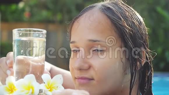 年轻的黑发美女在游泳池里放松慢慢地喝水1920x1080视频的预览图