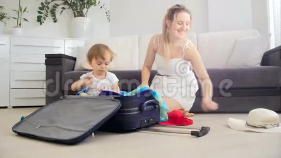 快乐的年轻妈妈带着她蹒跚学步的儿子打包暑假旅行箱视频的预览图
