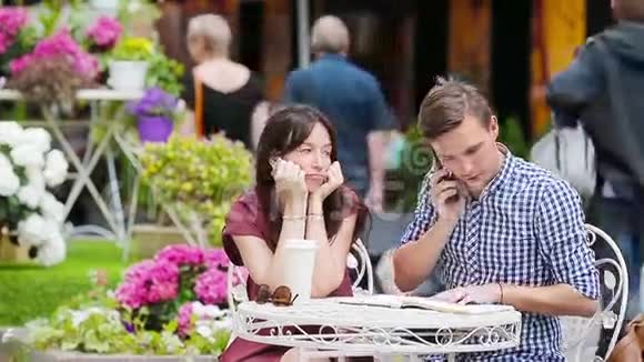 餐馆游客在户外咖啡馆情侣年轻女孩对男朋友伤心因为他忙于家务视频的预览图