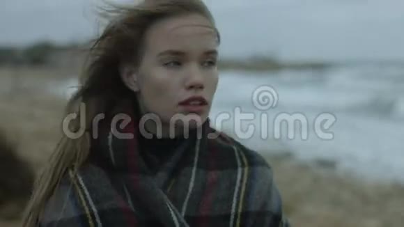 在冬天多风的天气里体贴的女孩站在海边视频的预览图