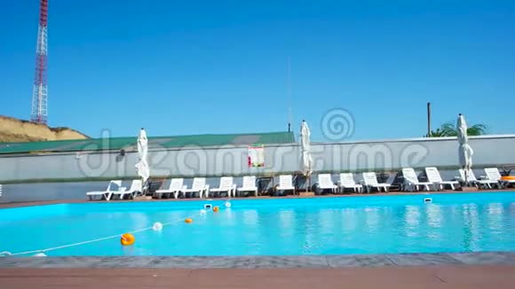 游泳池全景慢速运动蓝色水晶水休息室日光浴床和游泳池附近的雨伞视频的预览图
