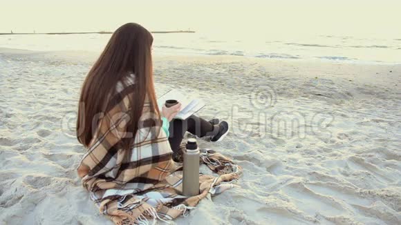 美丽的女人在海滩上喝茶读书视频的预览图