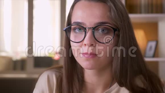 年轻貌美的白种人女学生戴着眼镜看着镜头在室内开心地笑着视频的预览图