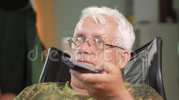 老人坐在皮椅上专心看电视戴着眼镜白发视频的预览图