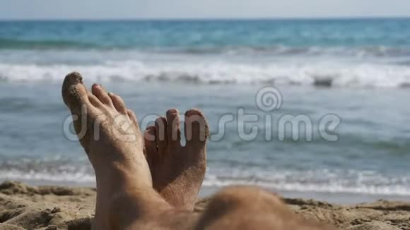 男人的腿躺在海边的海滩上波夫慢动作视频的预览图