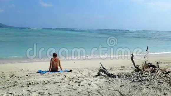 女孩坐在沙滩上观察海浪拍打视频的预览图