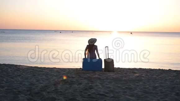 一个年轻的女人坐在靠近大海的手提箱上视频的预览图