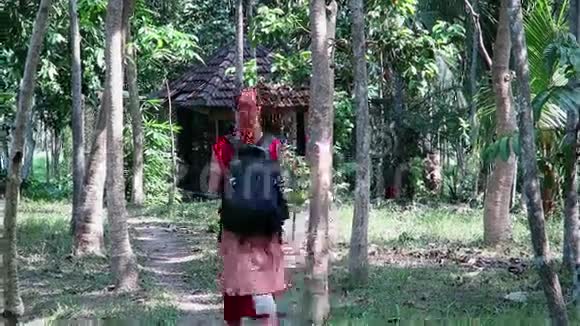 在巴厘岛乌布德背着背包走在一条穿过高大棕榈树的小路上的女孩视频的预览图
