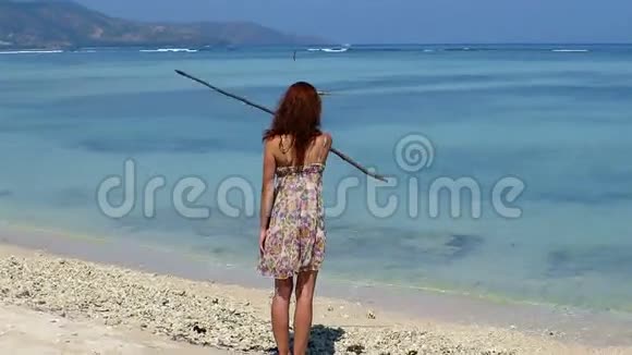 一个女孩站在沙滩上玩木枝视频的预览图