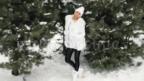 冬天穿着一件白色连衣裙在一棵绿树上摆姿势的高级模特视频的预览图