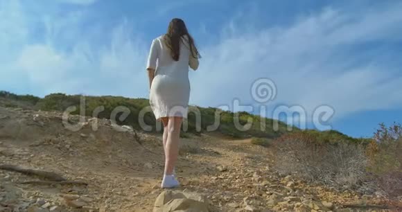 美丽的年轻女子在海边的荒山中散步视频的预览图