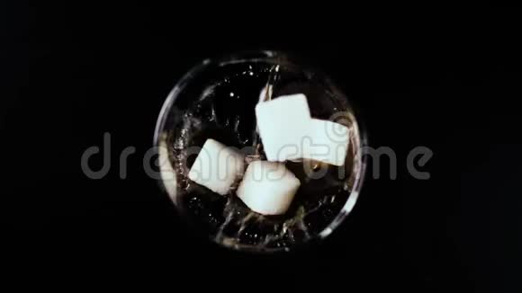 糖和可乐苏打水一起掉进玻璃杯里慢速运动俯视视频的预览图