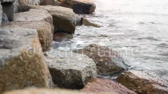 海水在沙滩上的石头间激起波浪视频的预览图