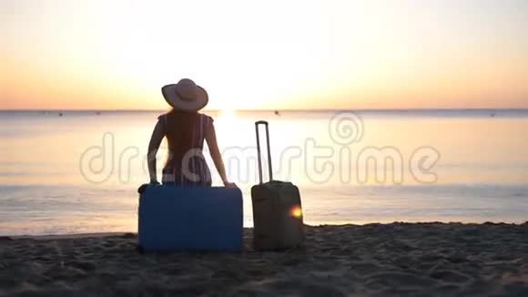 一个年轻的女人坐在靠近大海的手提箱上视频的预览图