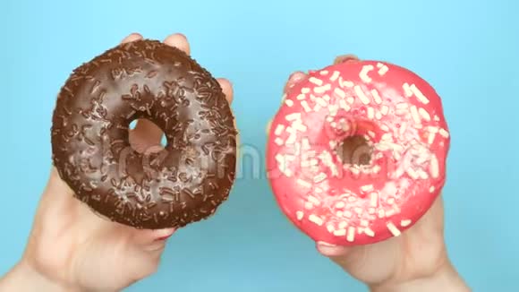 巧克力甜甜圈和草莓甜甜圈的概念选择有红色指甲油的女性手拿着粉红色和棕色甜甜圈视频的预览图